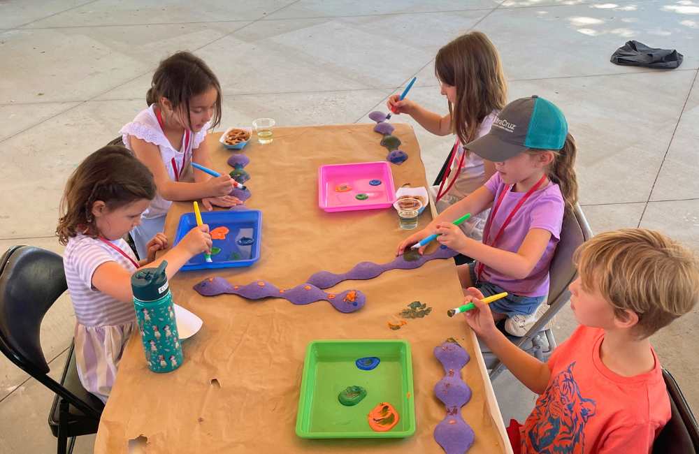 Children at zoo camp, sitting around a table working on a paint project.
